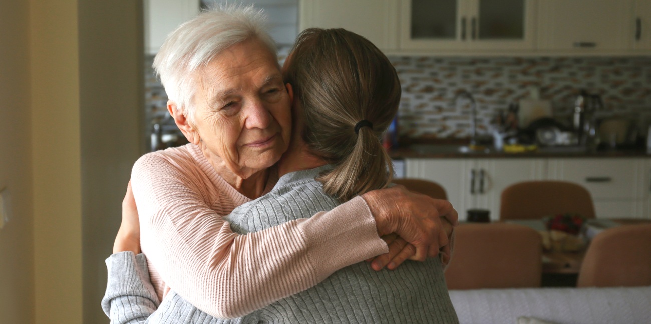 Elderly woman hugging daughter in kitchen of home